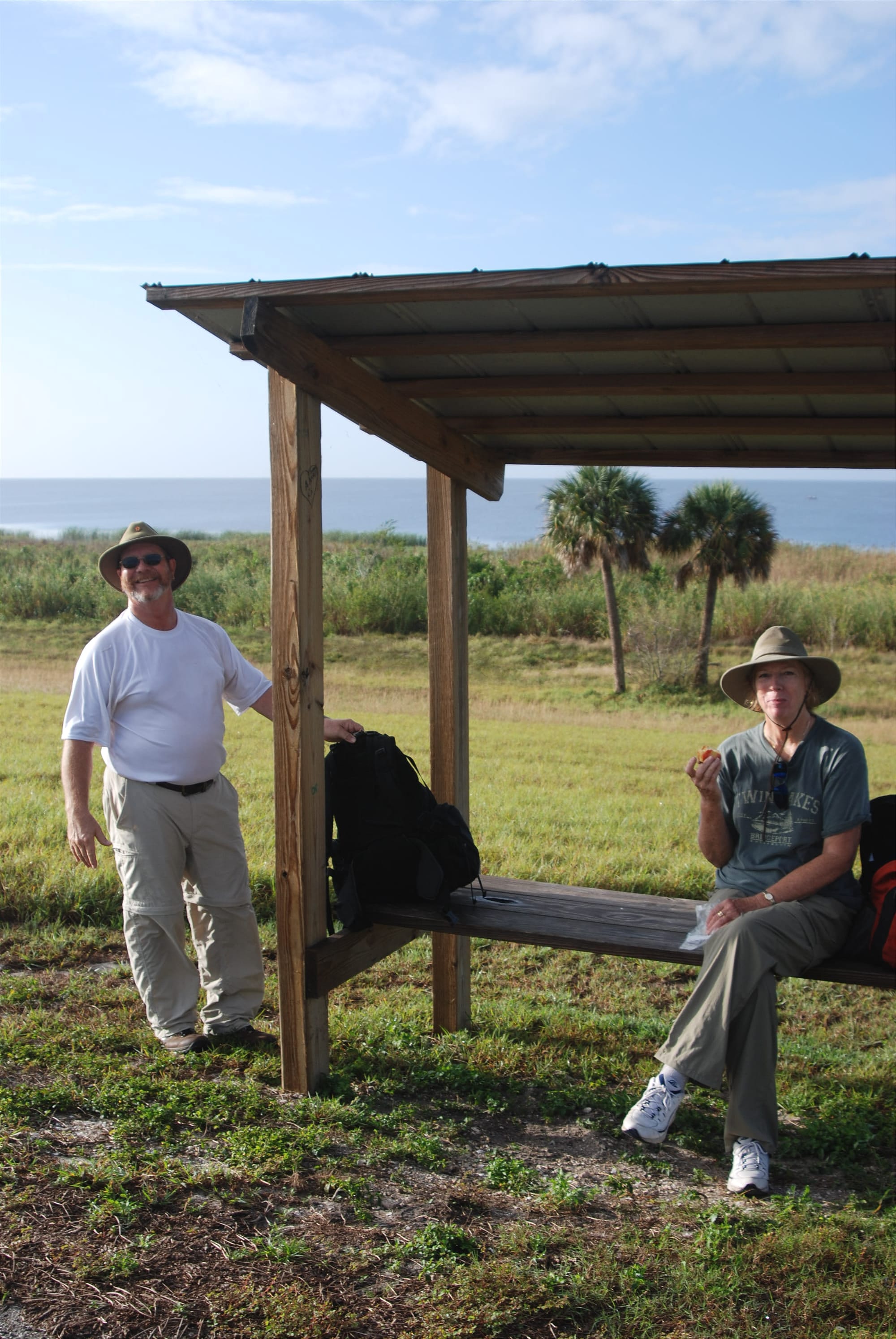 Smiling man with daypack and woman having a snack on a bench