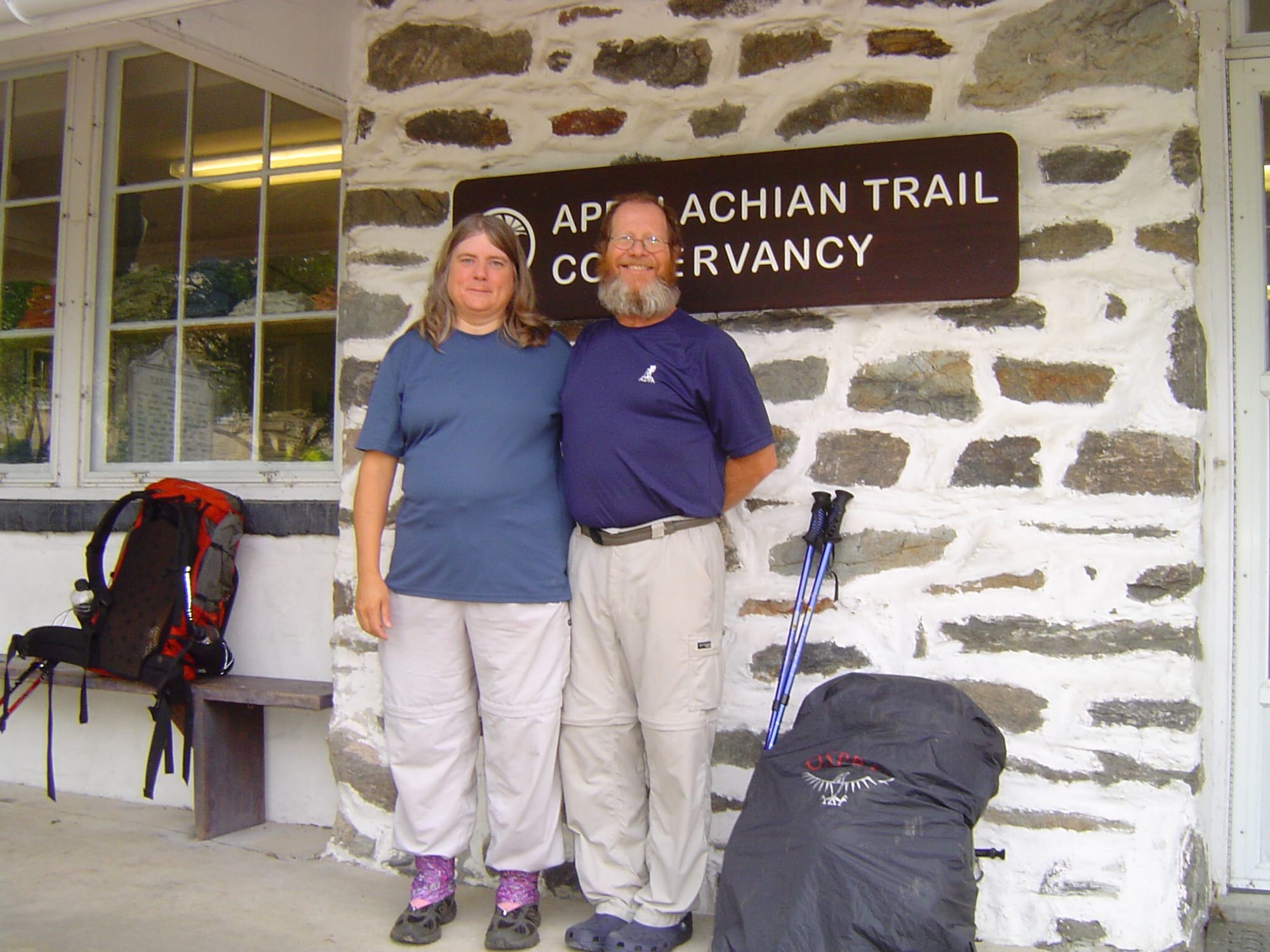 Woman and man backpackers in front of the Appalachian Trail Conservancy sign with their backpacks