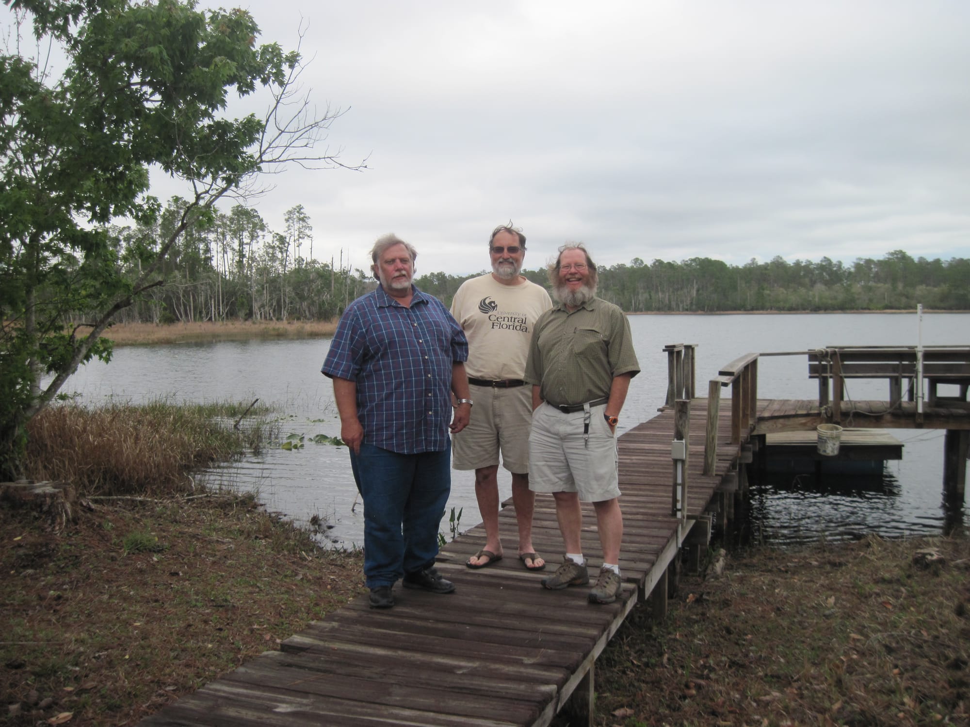Three men on a dock on a lake on a gloomy day