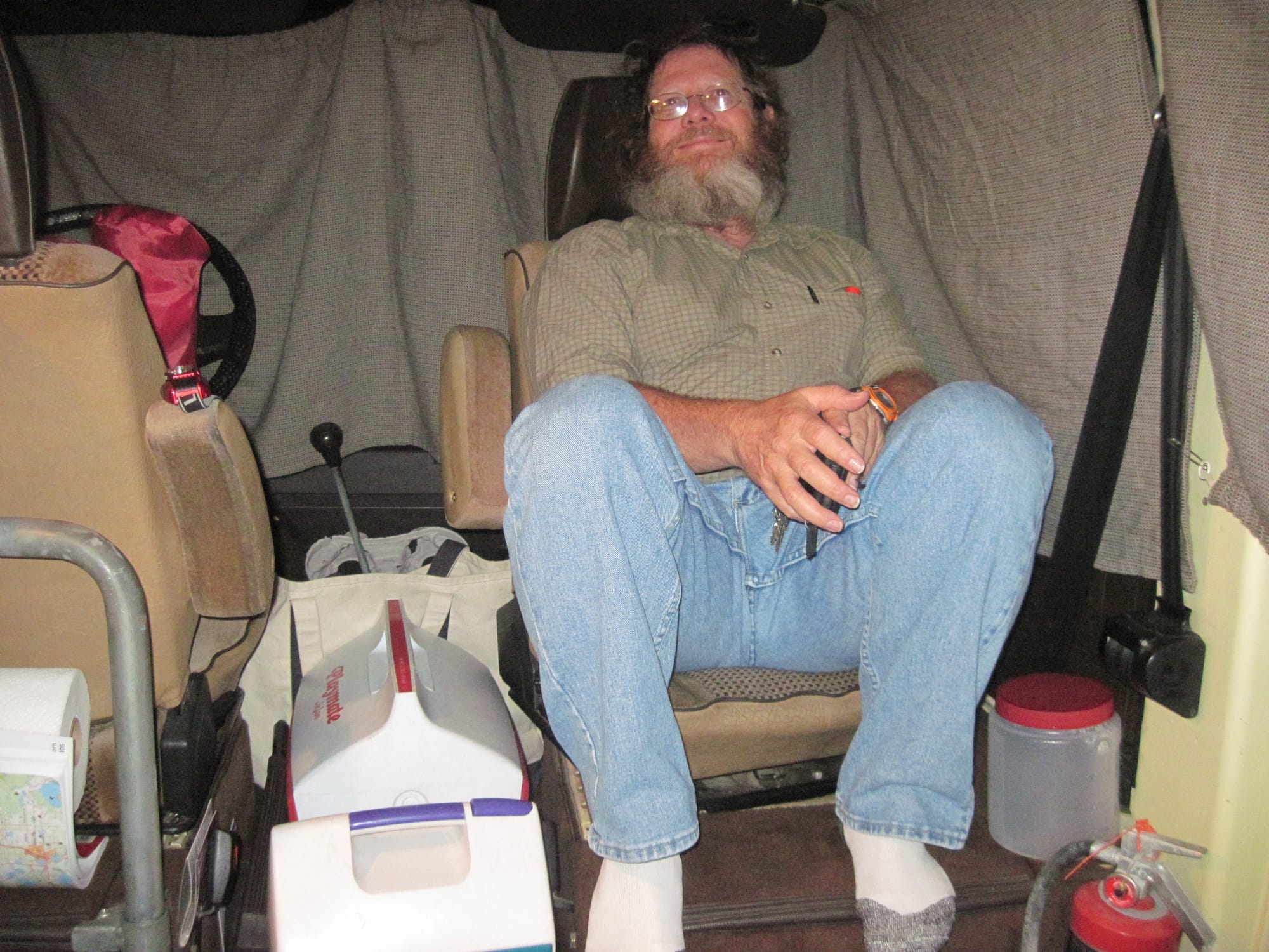 Man in a turned around front seat in a cluttered VW camper