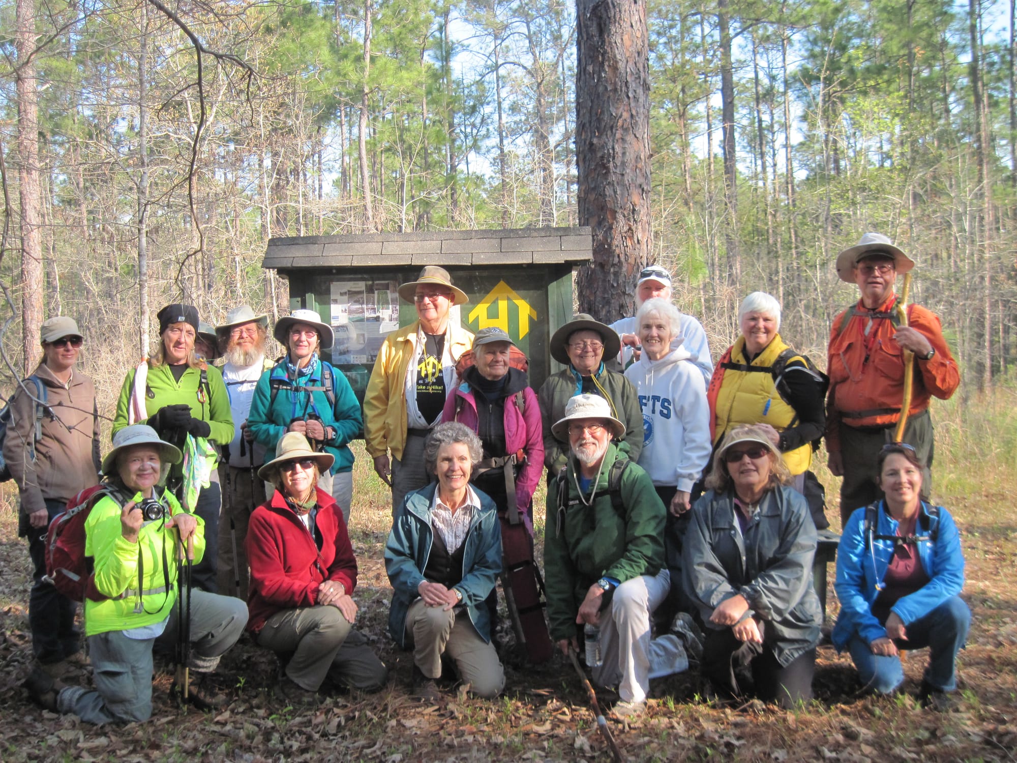 Hikers in jackets posed in front of a kiosk