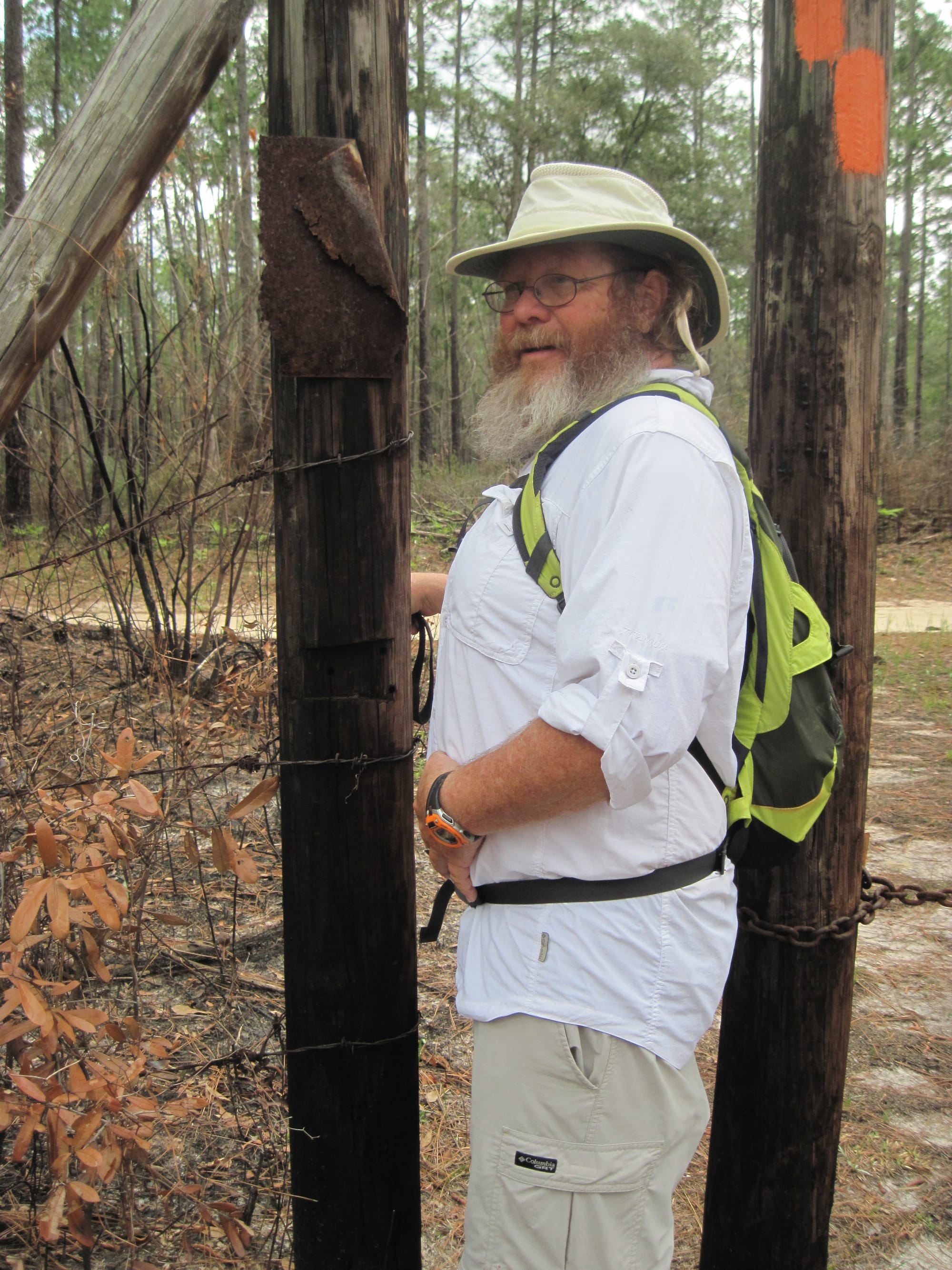 Man trying to squeeze through a hiker pass-thru edged with barbed wire