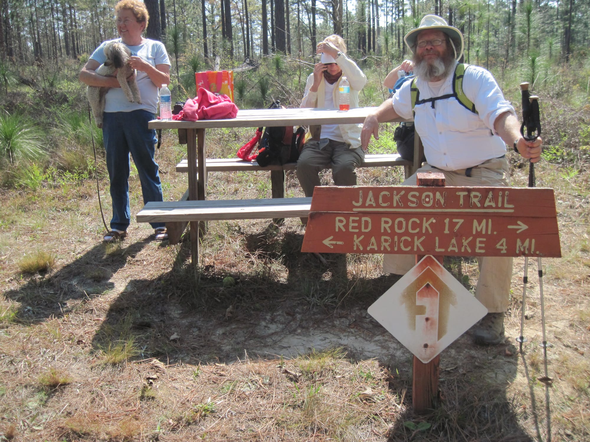 Man and two women at trail junction sign and picnic table