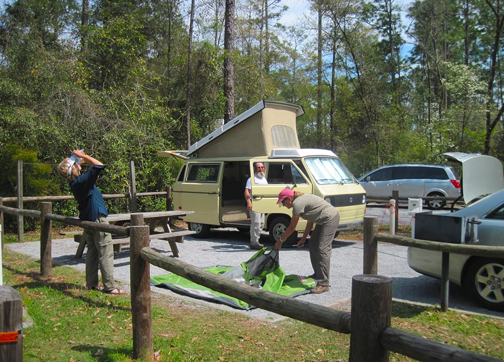 Woman setting up a tent next to a VW camper van