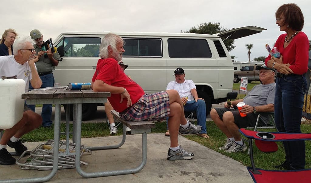 Folks gathered around a picnic table in front of a VW camper