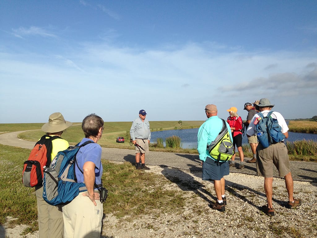 Man addressing group of hikers along a curved levee