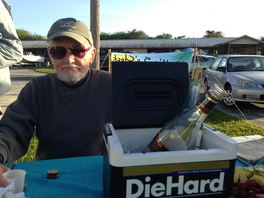 Man with a cup and a cooler with a bottle of wine