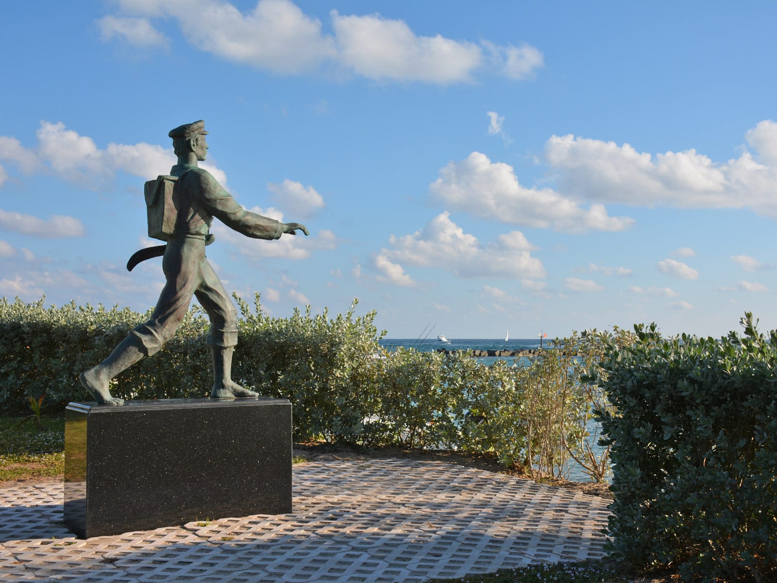 Statue of mailman in old-time clothing facing waterfront