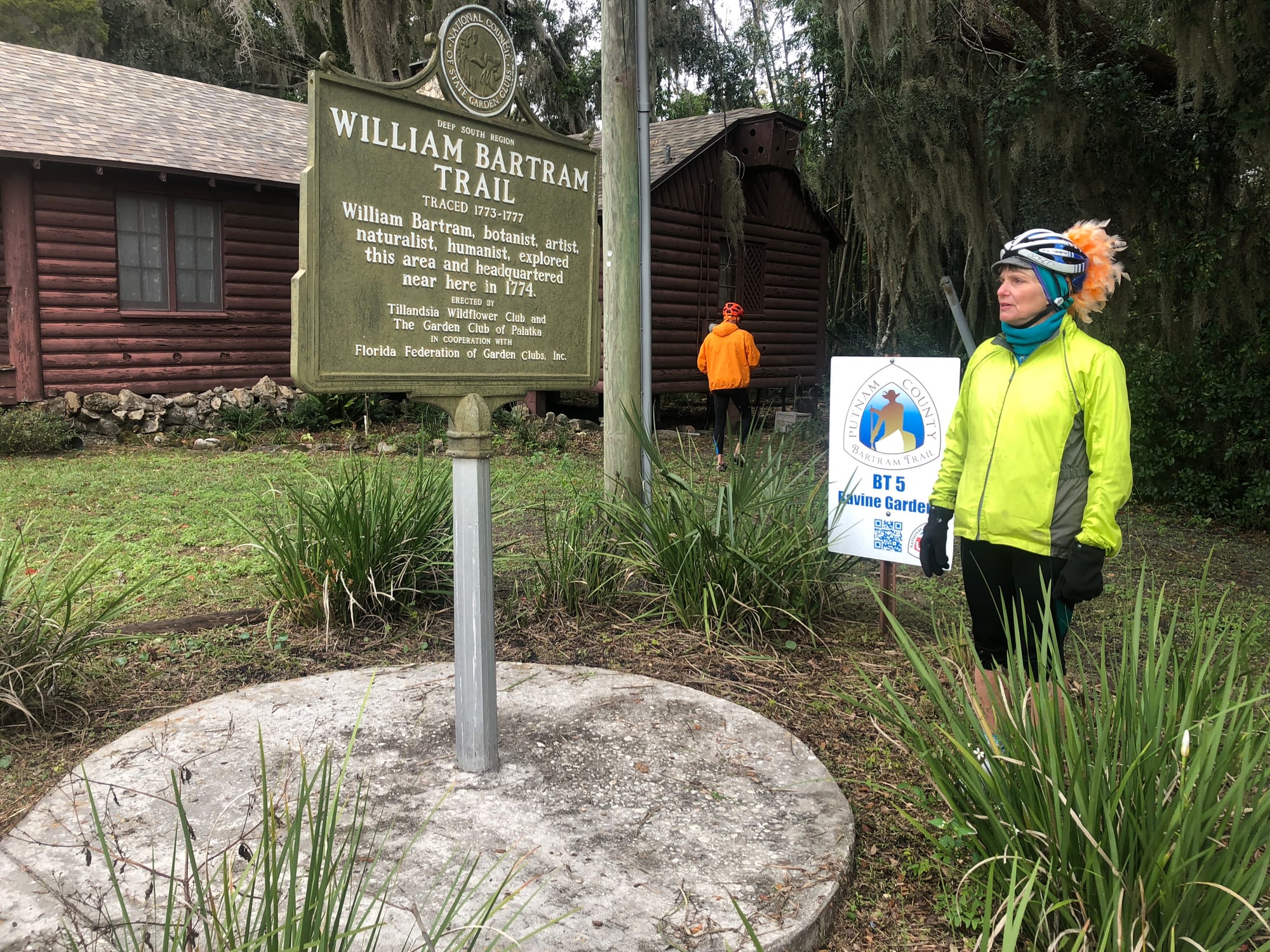 Cyclist in bright jacket looks at historic marker