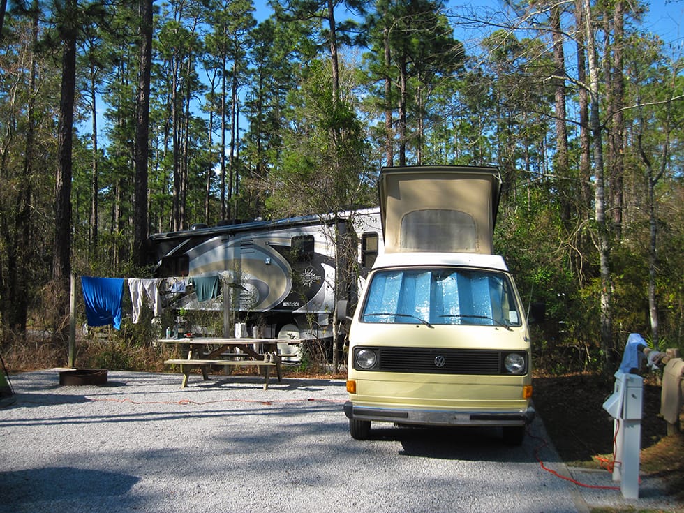 Small camper van in front of huge RV