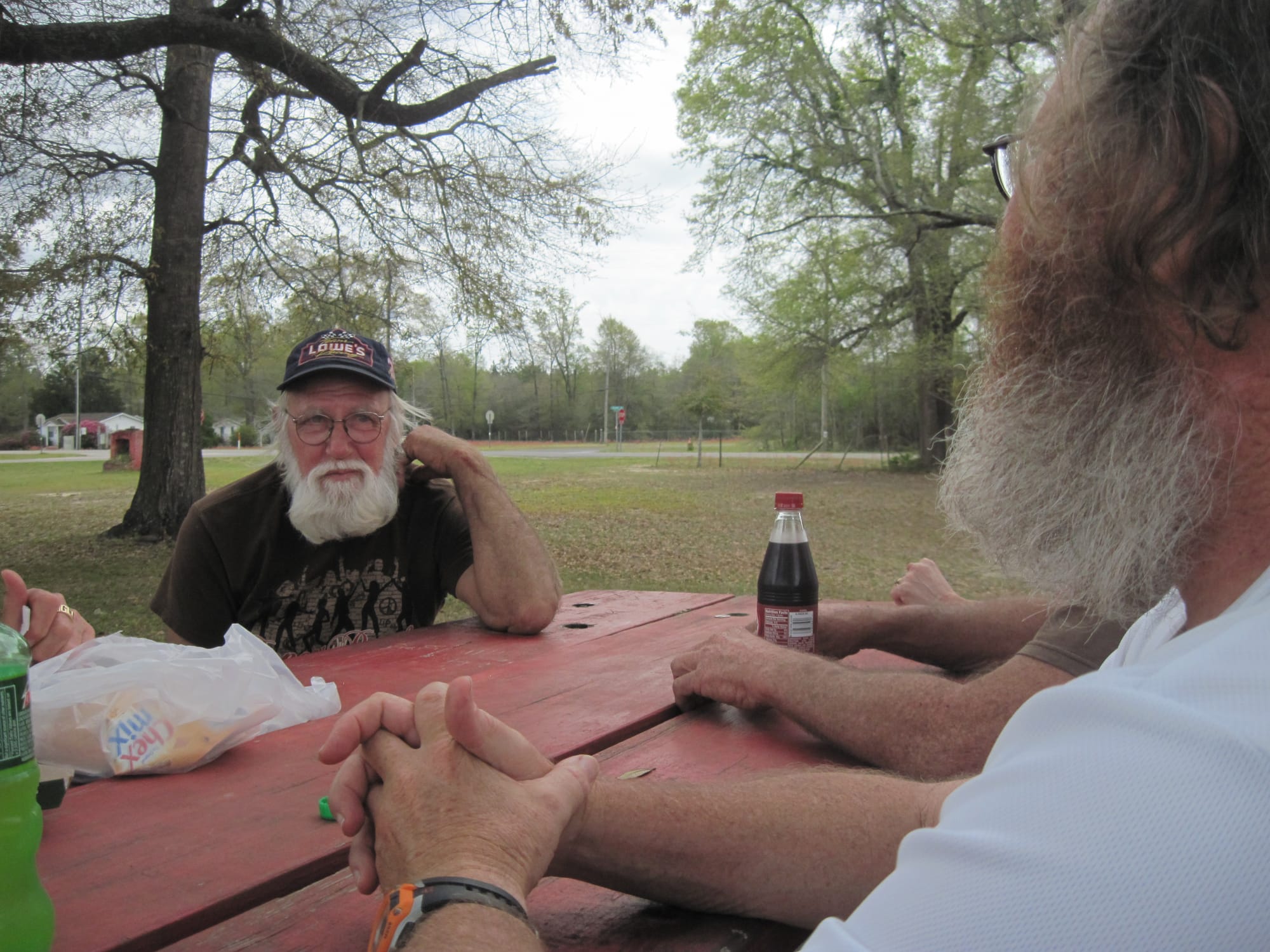 Two bearded men looking across at each other at a picnic table