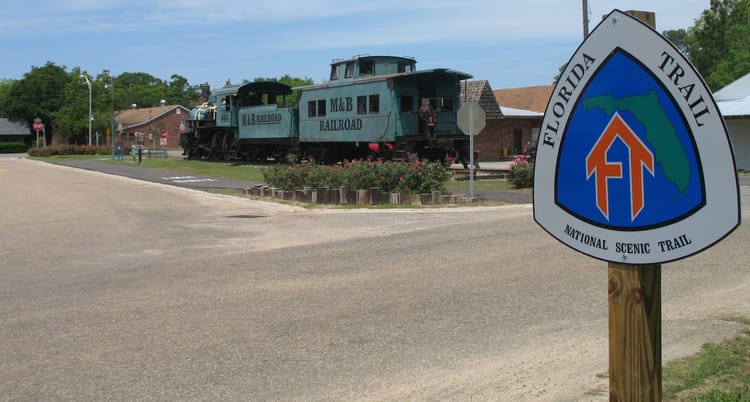 Florida Trail sign with engine and caboose of M&B Railroad beyond