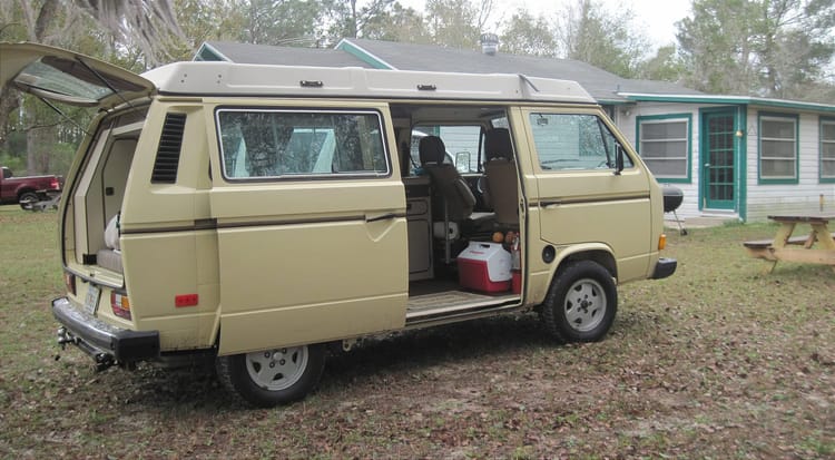 Westfalia camper with slider and back door open parked outside a cabin