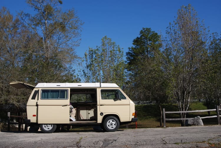 Vintage VW Westfalia under blue skies at a park with slider and back doors open