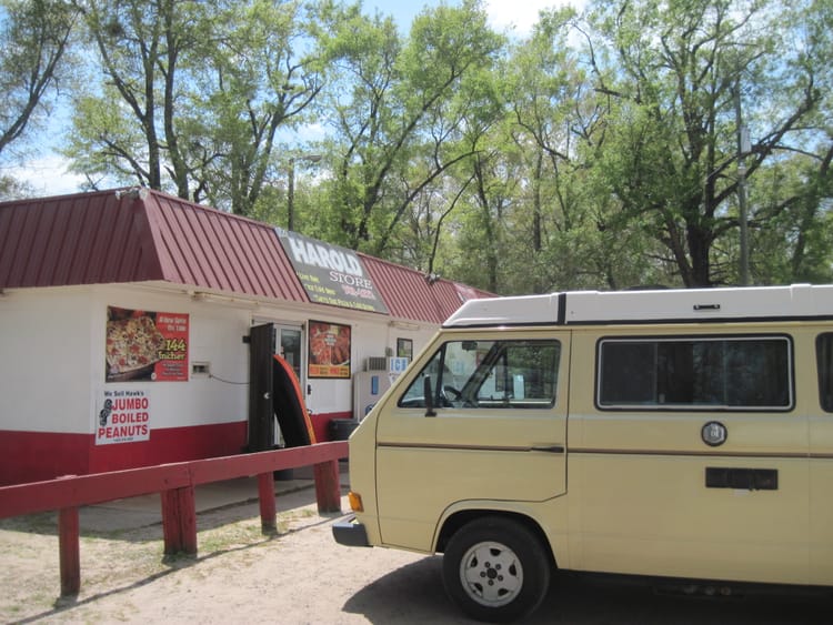VW camper van in front of small convenience store with a red roof