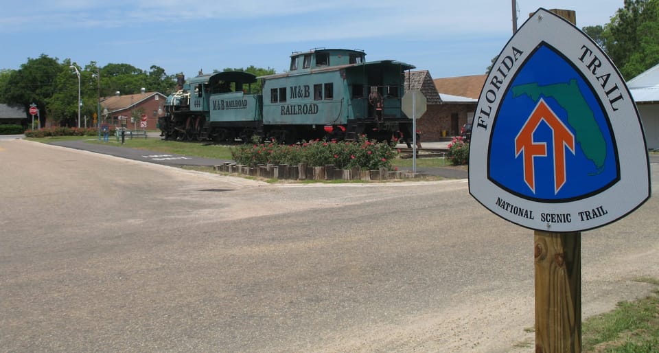 Florida Trail sign with engine and caboose of M&B Railroad beyond