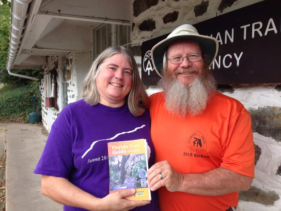 Woman and man holding a hiking guide in front of the Appalachian Trail office in Harpers Ferry WV