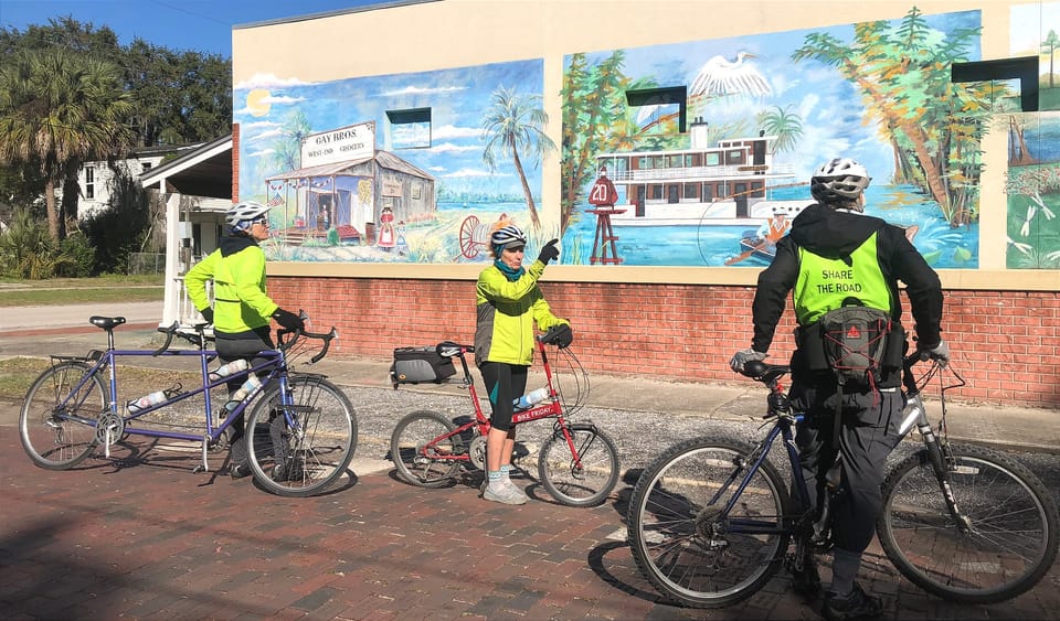 Cyclists looking at a colorful mural along a brick street