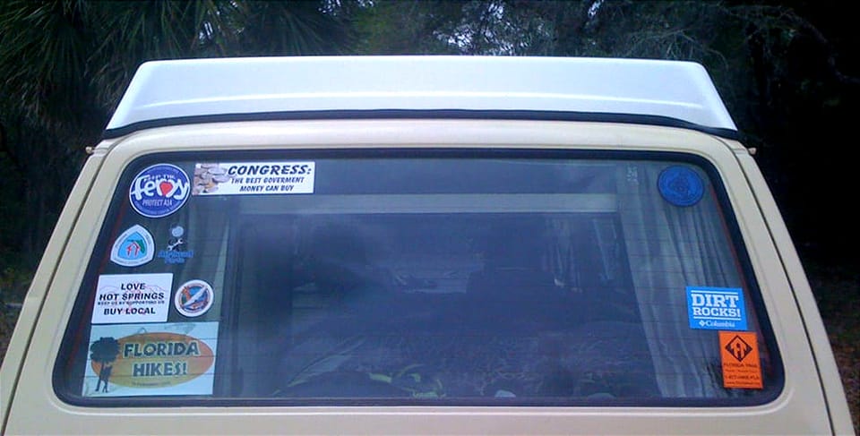 Back window of a VW Westfalia with stickers on it