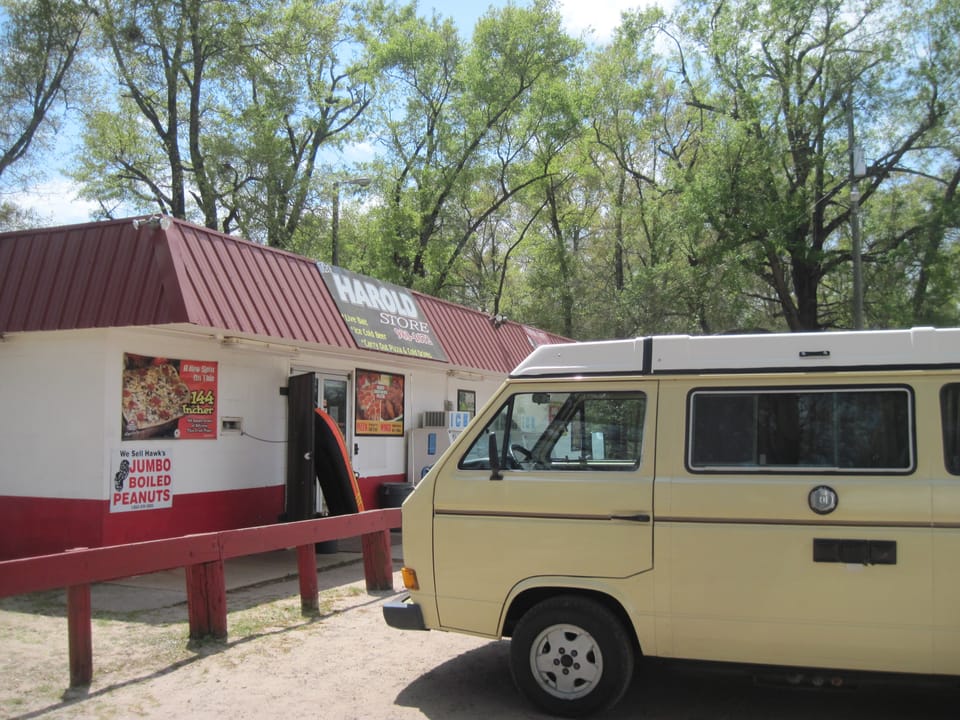 VW camper van in front of small convenience store with a red roof