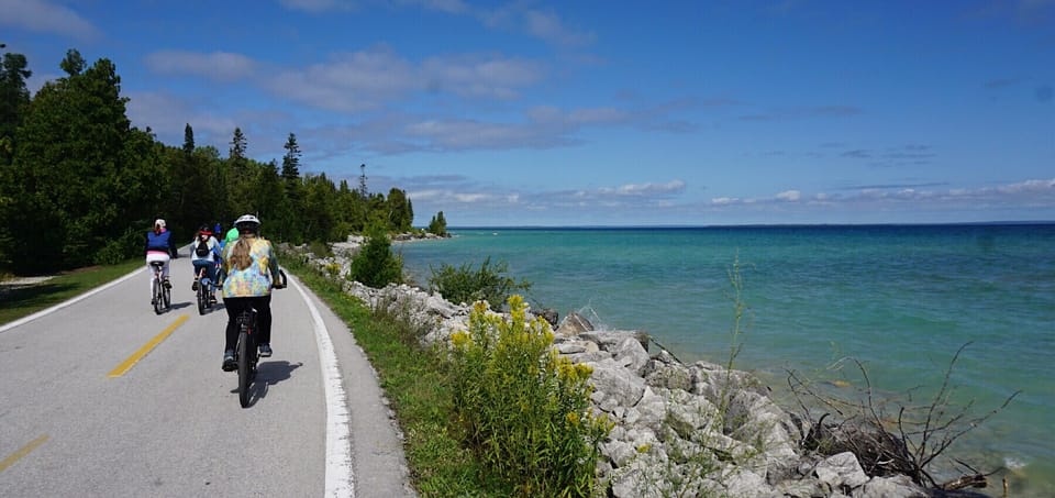 Cyclists riding a highway next to aquamarine waters
